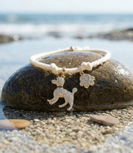 Gold-tone pavé dog and paw charm bracelet on cream cotton cord, adjustable closure