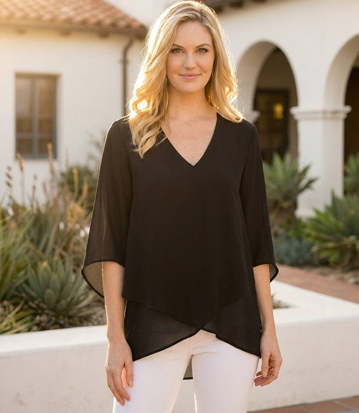 Woman wearing a silky crepe Bracelet Sleeve Asymmetric Top with flare sleeves and layered asymmetrical hem