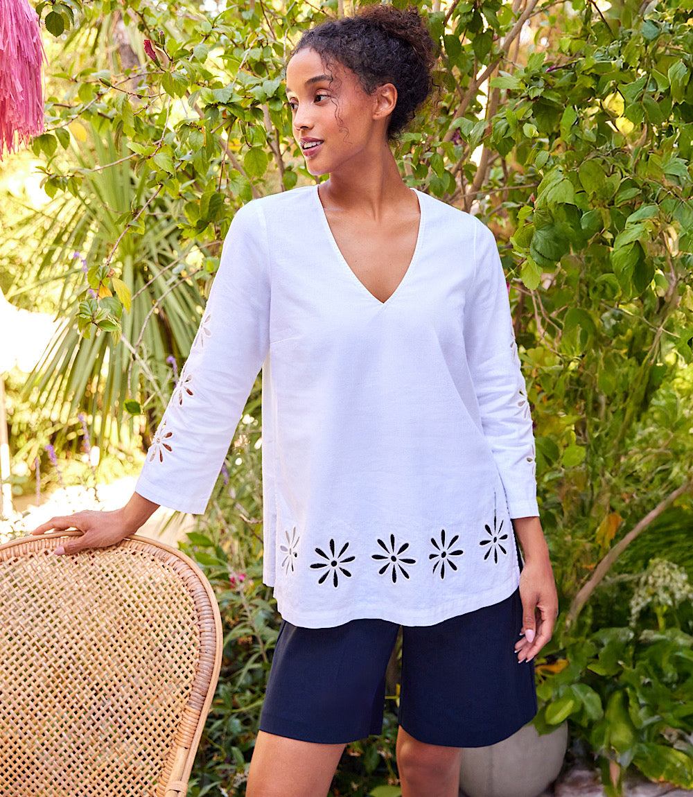 Woman wearing white cutout embroidered flower detail tunic with V-neck and three-quarter sleeves outdoors