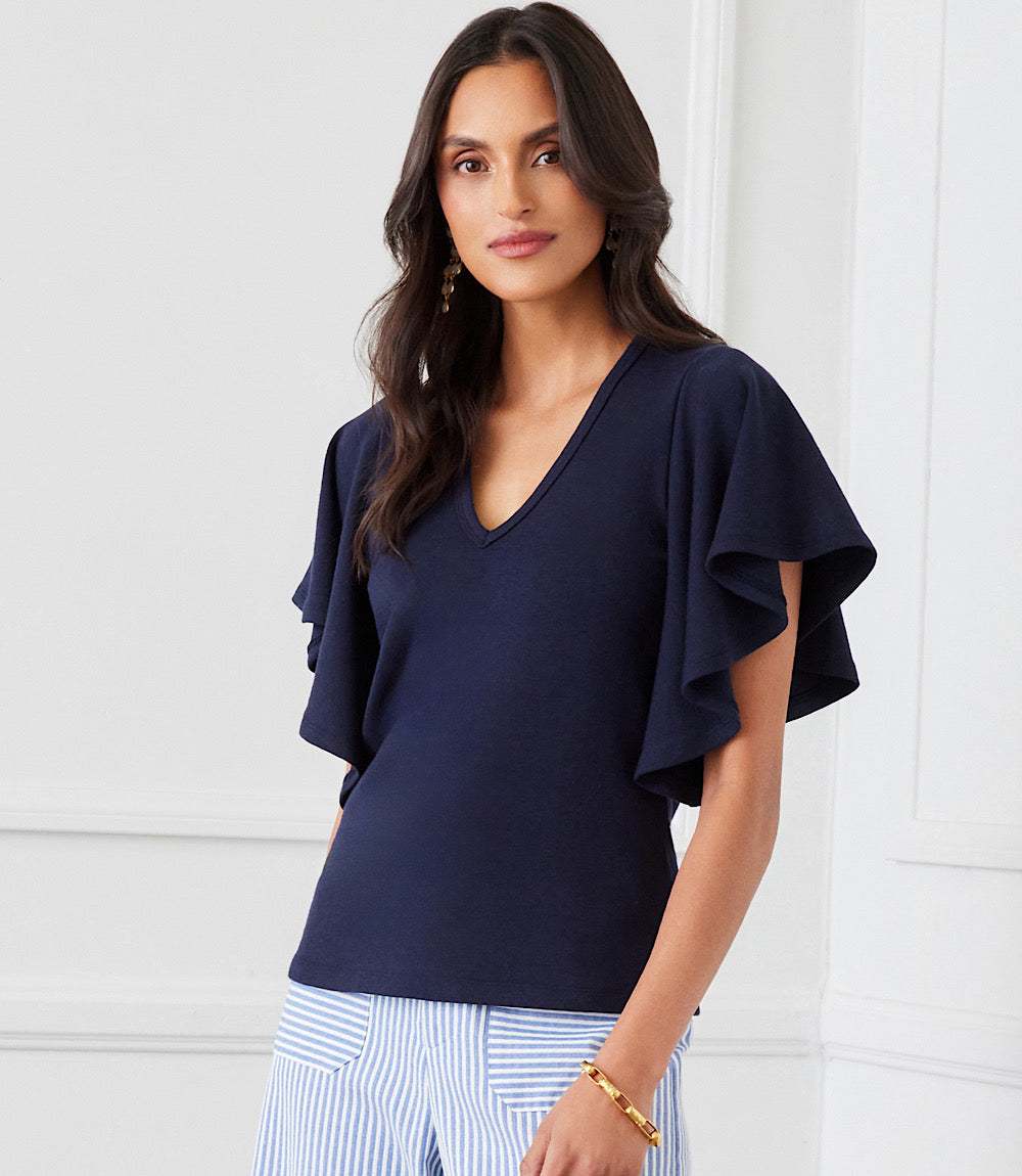 Woman wearing navy blue Flutter Sleeve V-Neck Top made of organic cotton with ruffled sleeves