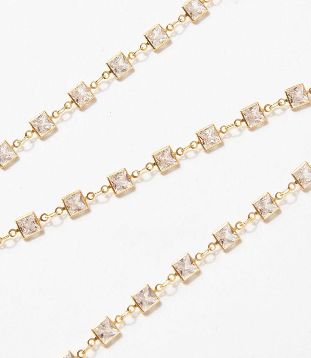 Square crystal chain necklace with square-cut crystals set in brass links on a white background