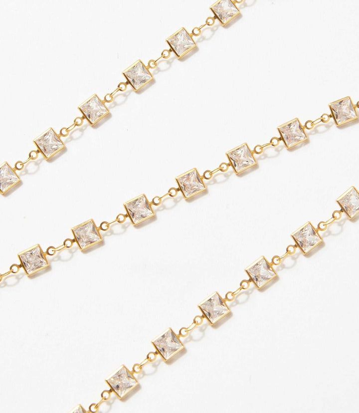 Square crystal chain necklace with square-cut crystals set in brass links on a white background