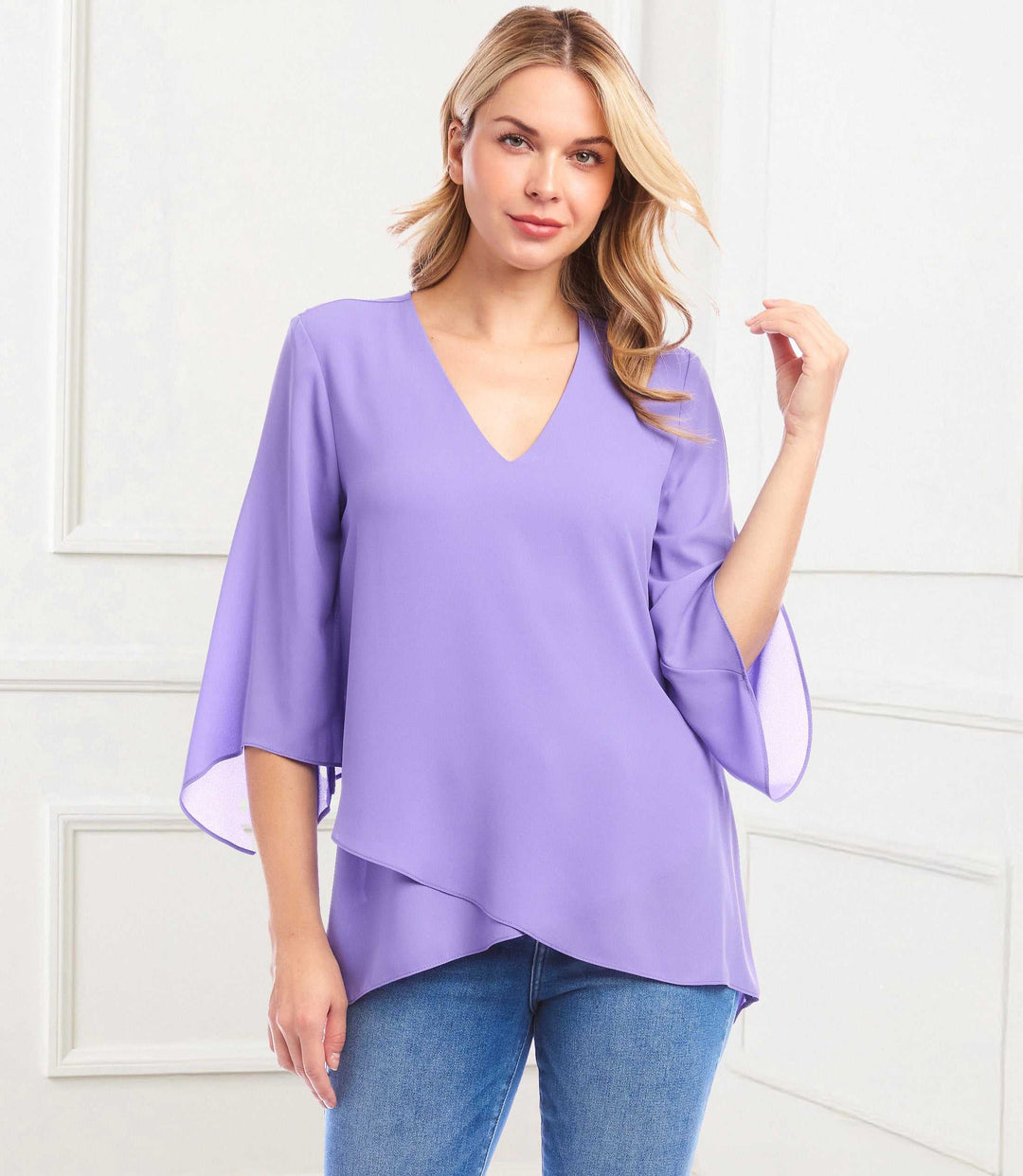 Woman wearing a lavender silky crepe bracelet sleeve asymmetric top with V-neck and layered hem