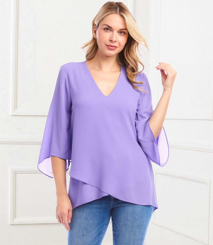 Woman wearing a lavender silky crepe bracelet sleeve asymmetric top with V-neck and layered hem