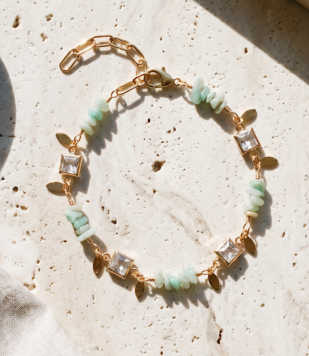 Crystal and gemstone bracelet with aqua gemstones, crystal accents, gold paperclip chain, and lobster clasp on white background