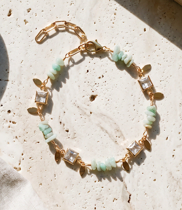 Crystal and gemstone bracelet with aqua gemstones, crystal accents, gold paperclip chain, and lobster clasp on white background