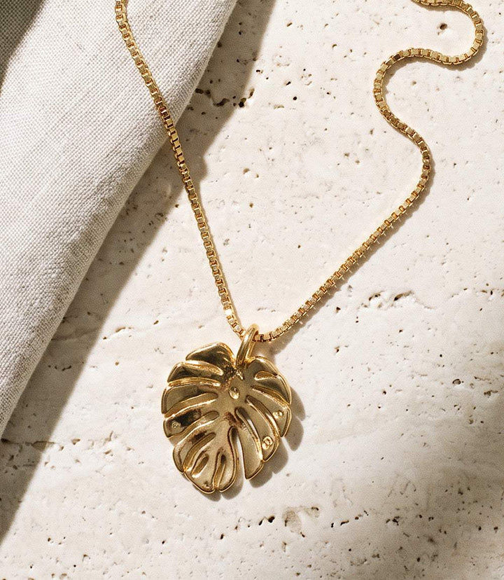 Tropical leaf charm necklace with gold-plated brass pendant and silver chain, elegant island-inspired jewelry accessory