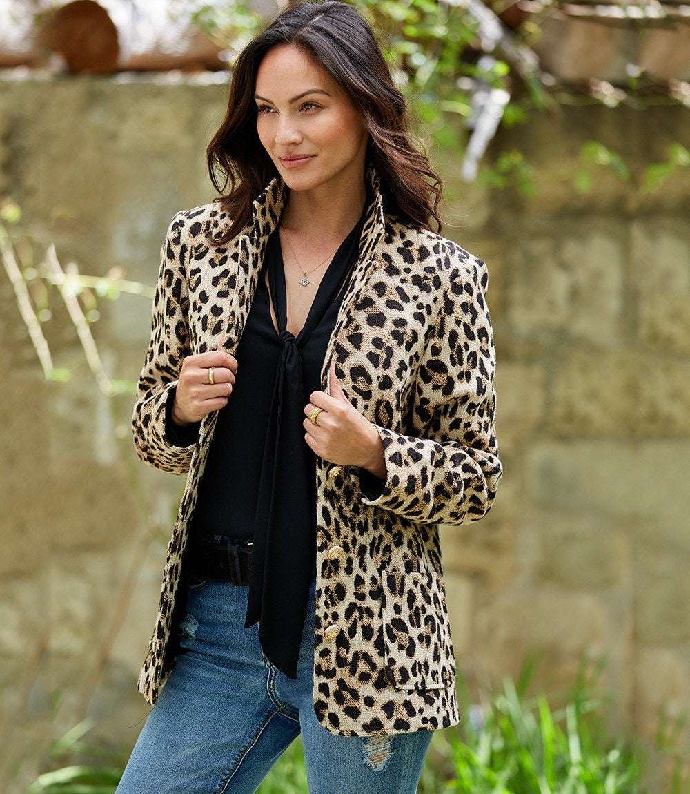 Woman wearing a tailored animal jacquard blazer with leopard print, button front, collared design, and front pockets.