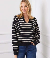 Woman wearing a relaxed fit black and cream stripe polo sweater with drop shoulders and ribbed cuffs and hem