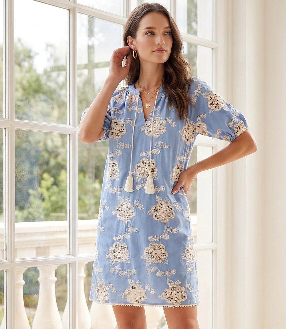 Woman wearing a light puff sleeve tassel dress with tie neck and relaxed fit above the knee