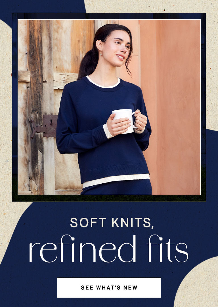 Woman wearing a navy blue sweater holding a white mug, with text 'Soft knits, refined fits' on a beige background.