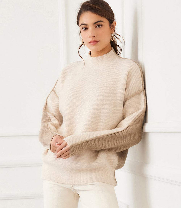 Woman wearing beige colorblock mock neck sweater with relaxed fit and drop shoulder sleeves