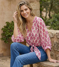 Blouson sleeve tie-front top with pink floral batik print, V-neck, and tie-knot detail on cream cotton fabric