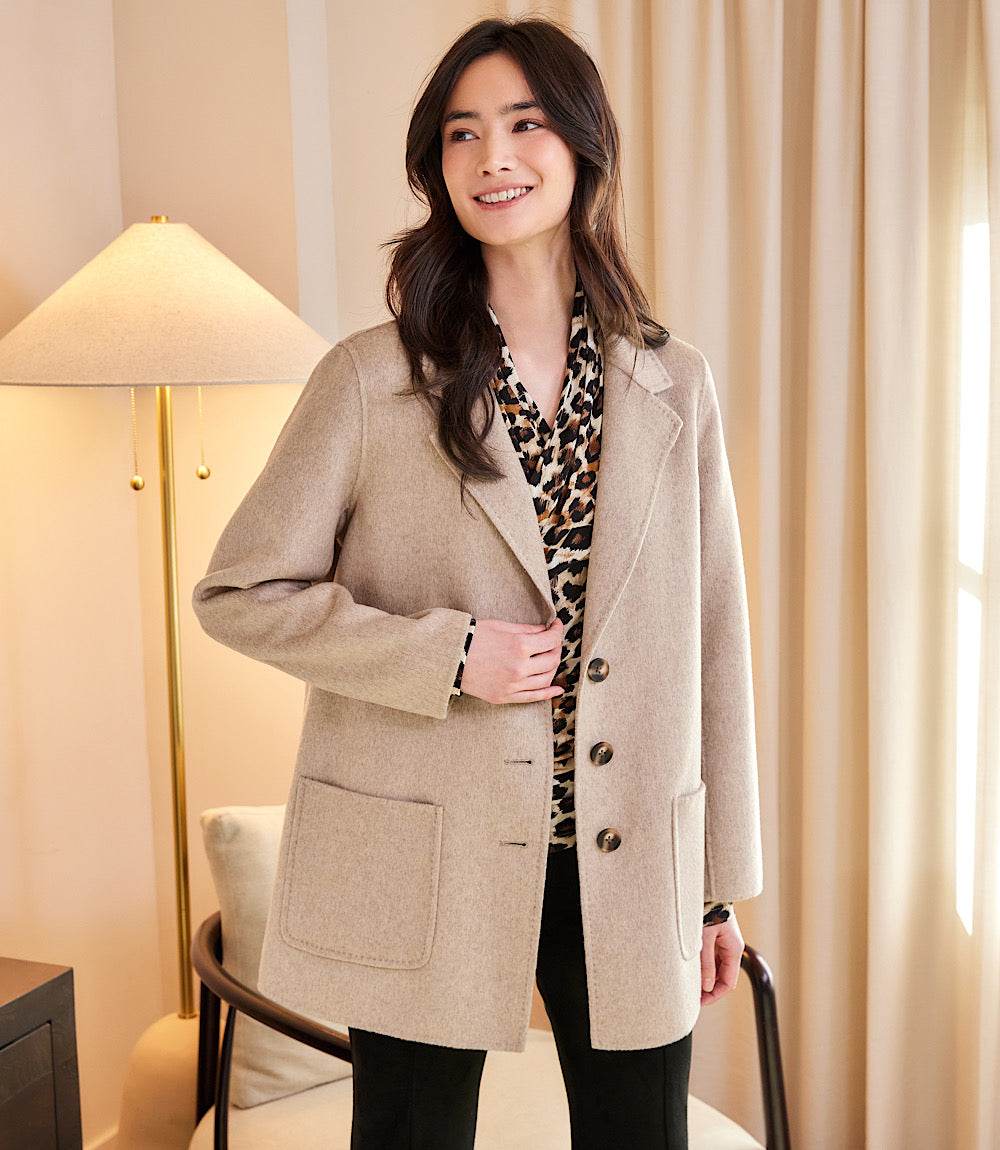 Woman wearing oversized brushed blazer in beige with three buttons and front patch pockets indoors
