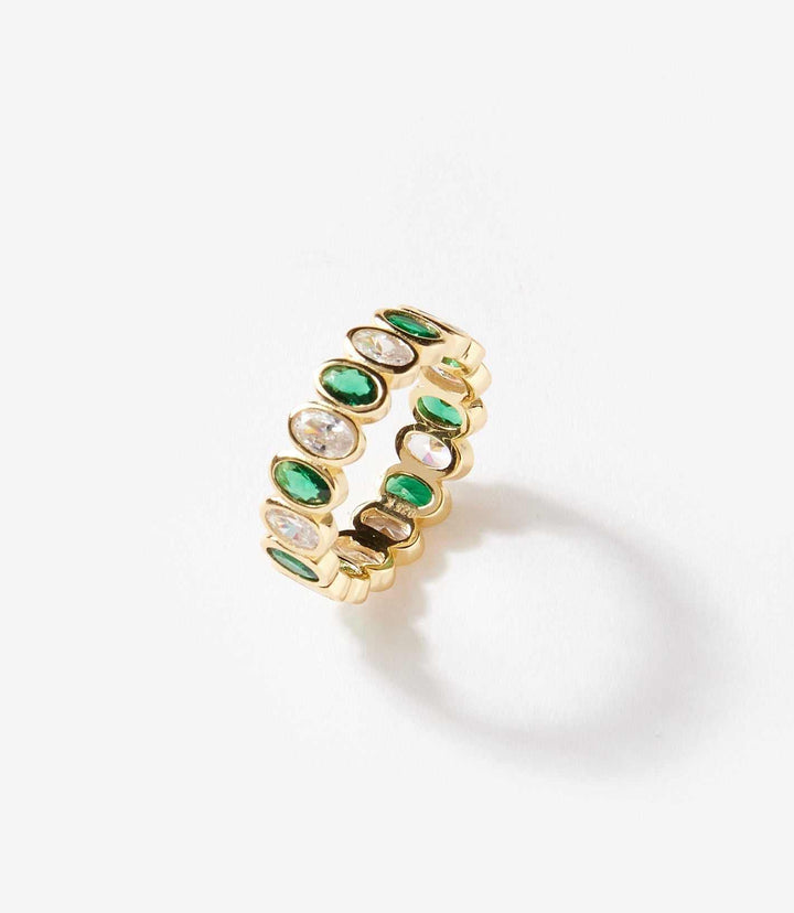 Gold gemstone ring with alternating emerald and clear glass crystal stones in a minimalist band design