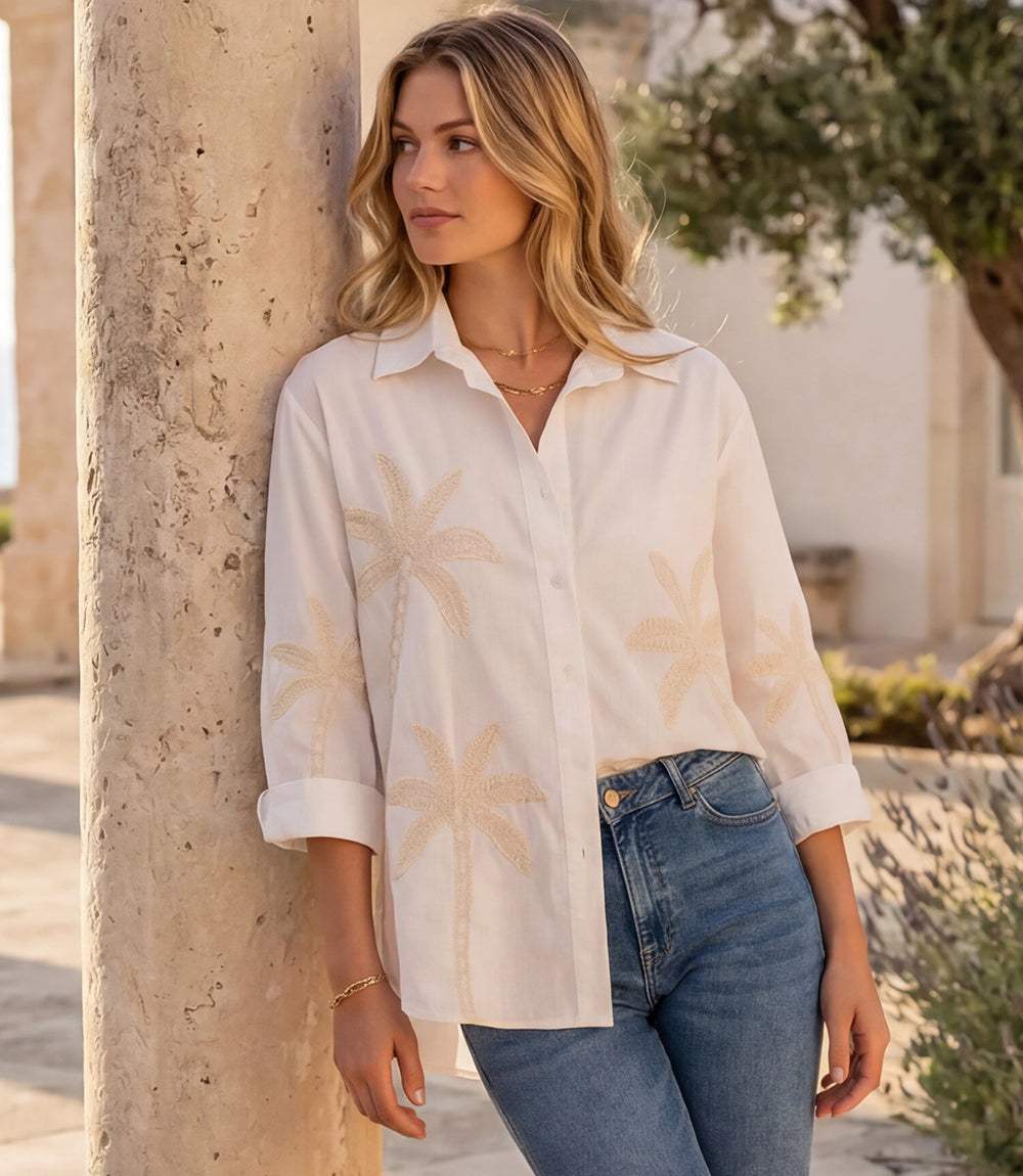 Woman wearing a bell sleeve embroidered palm tree shirt with button front and classic collar