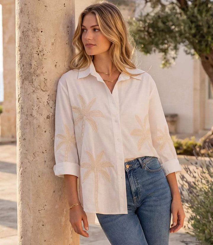 Woman wearing a bell sleeve embroidered palm tree shirt with button front and classic collar
