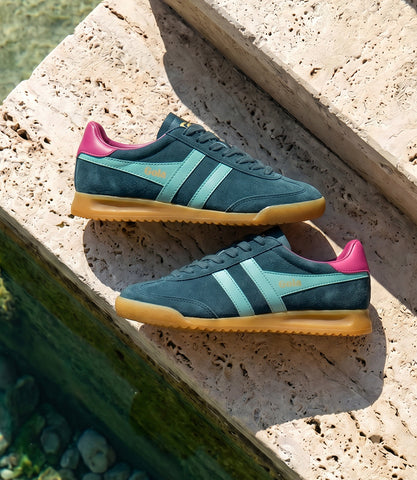 Teal and pink sneakers with brown soles on a stone surface