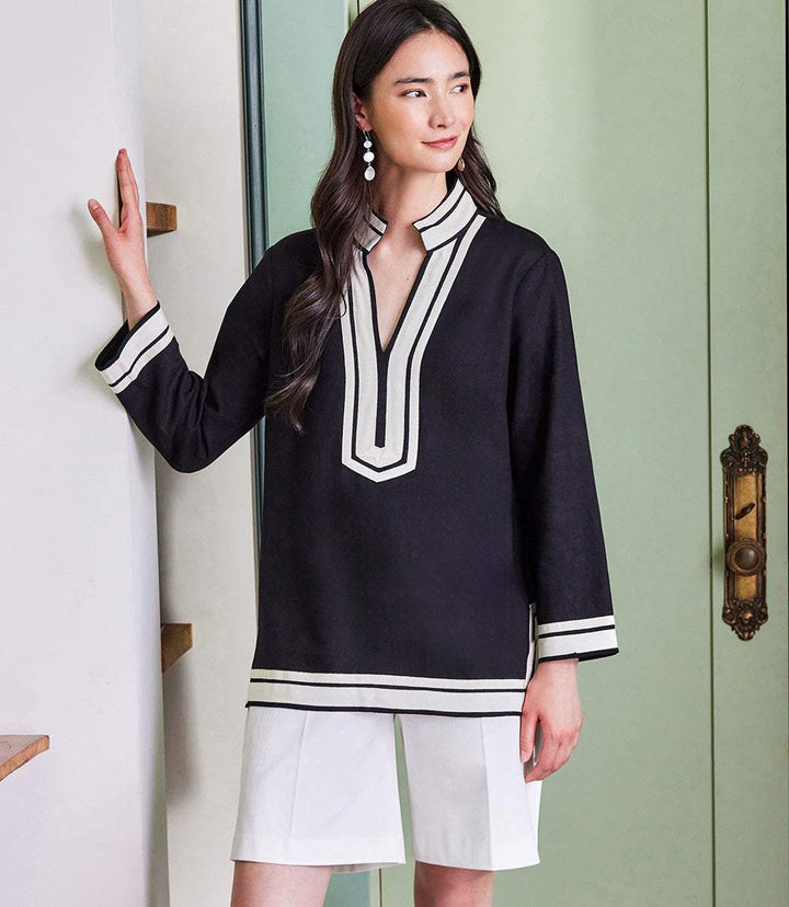 Woman wearing The St. Tropez Tunic in black with white grosgrain ribbon trim, paired with white shorts.