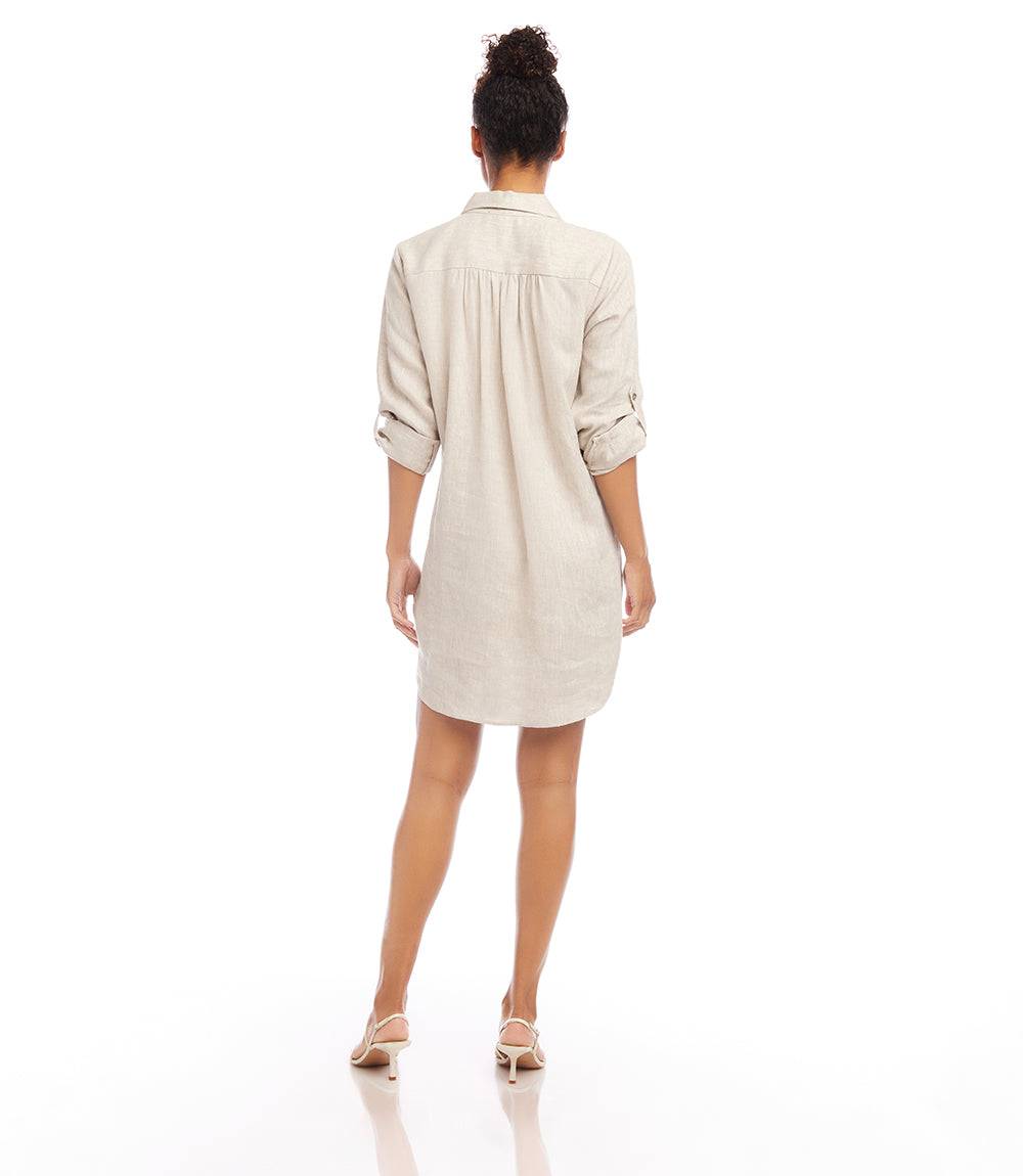 Back view of a woman wearing a relaxed fit oatmeal roll tab linen shirtdress with collared neckline and shirttail hem