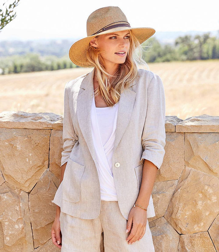 Woman wearing oatmeal linen ruched sleeve jacket with notch collar and front patch pockets outdoors
