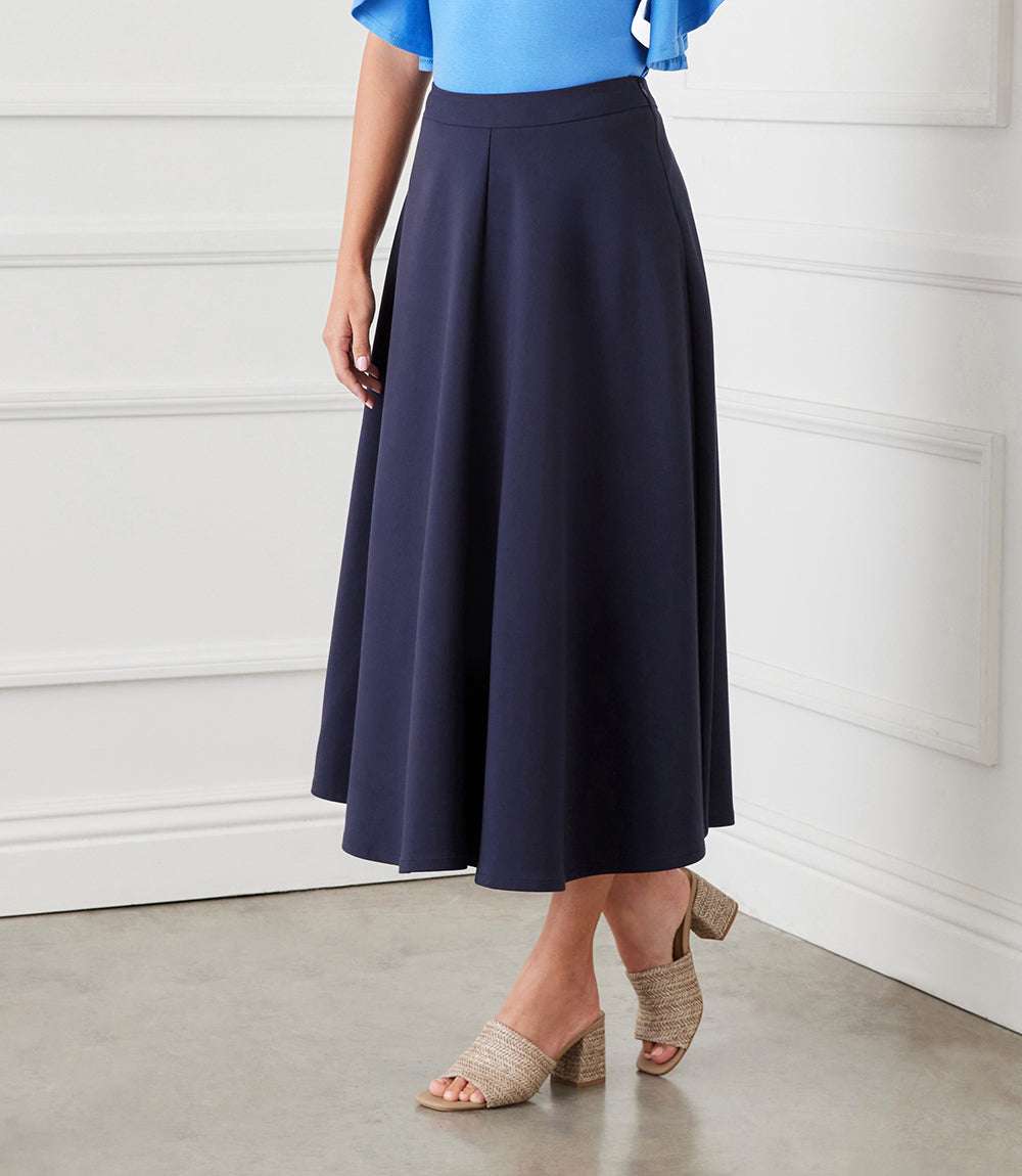Navy blue midi circle skirt with elastic waistband and side zipper closure worn with a blue top and beige heeled sandals