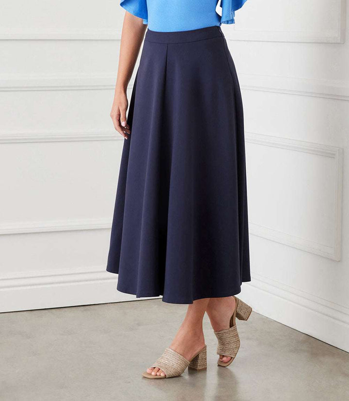 Navy blue midi circle skirt with elastic waistband and side zipper closure worn with a blue top and beige heeled sandals