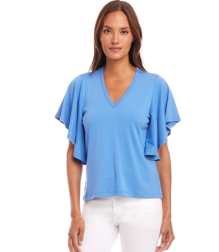 Woman wearing blue Flutter Sleeve V-Neck top with ruffled sleeves and white pants