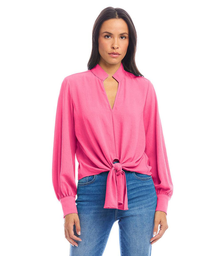 Woman wearing pink long sleeve tie-front top with mandarin collar and blue jeans
