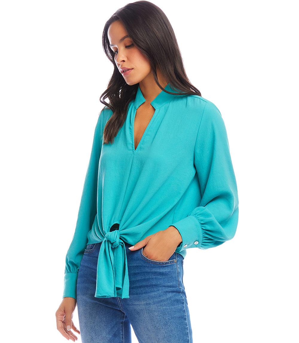 Woman wearing a teal long sleeve tie-front top with mandarin collar and jeans