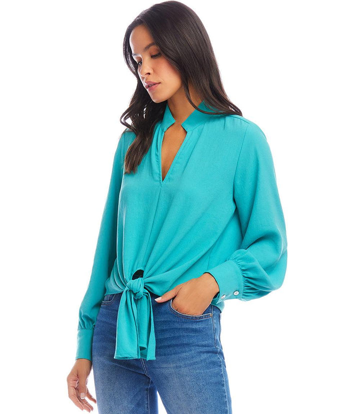 Woman wearing a teal long sleeve tie-front top with mandarin collar and jeans