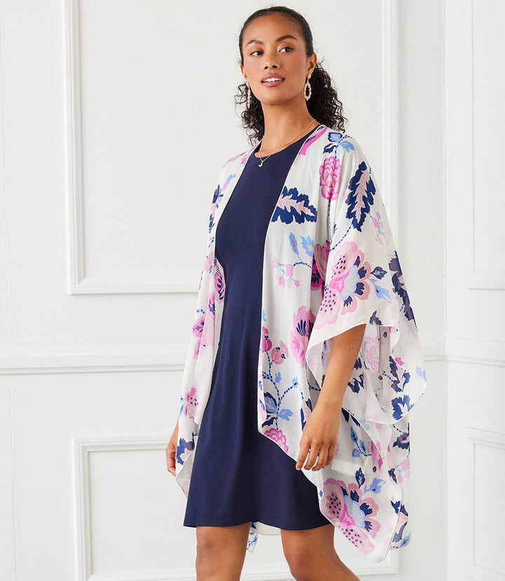 Woman wearing semi-sheer open front jacket with floral print and asymmetric hem over navy dress
