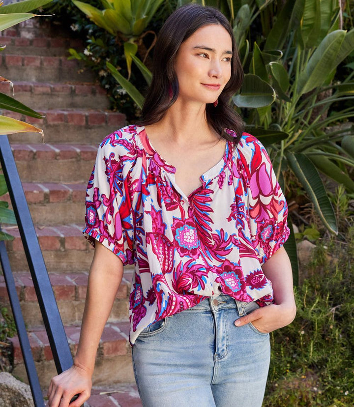 Woman wearing a colorful short sleeve peasant top with peony paisley print and puff sleeves.