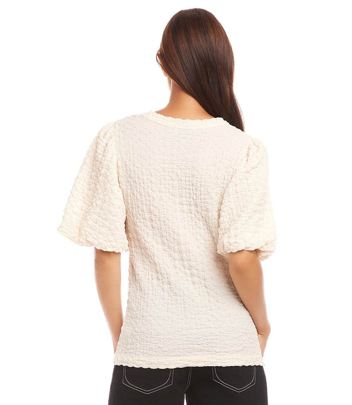 Back view of petite size puff sleeve textured top in cream with bubble texture knit and crew neck.