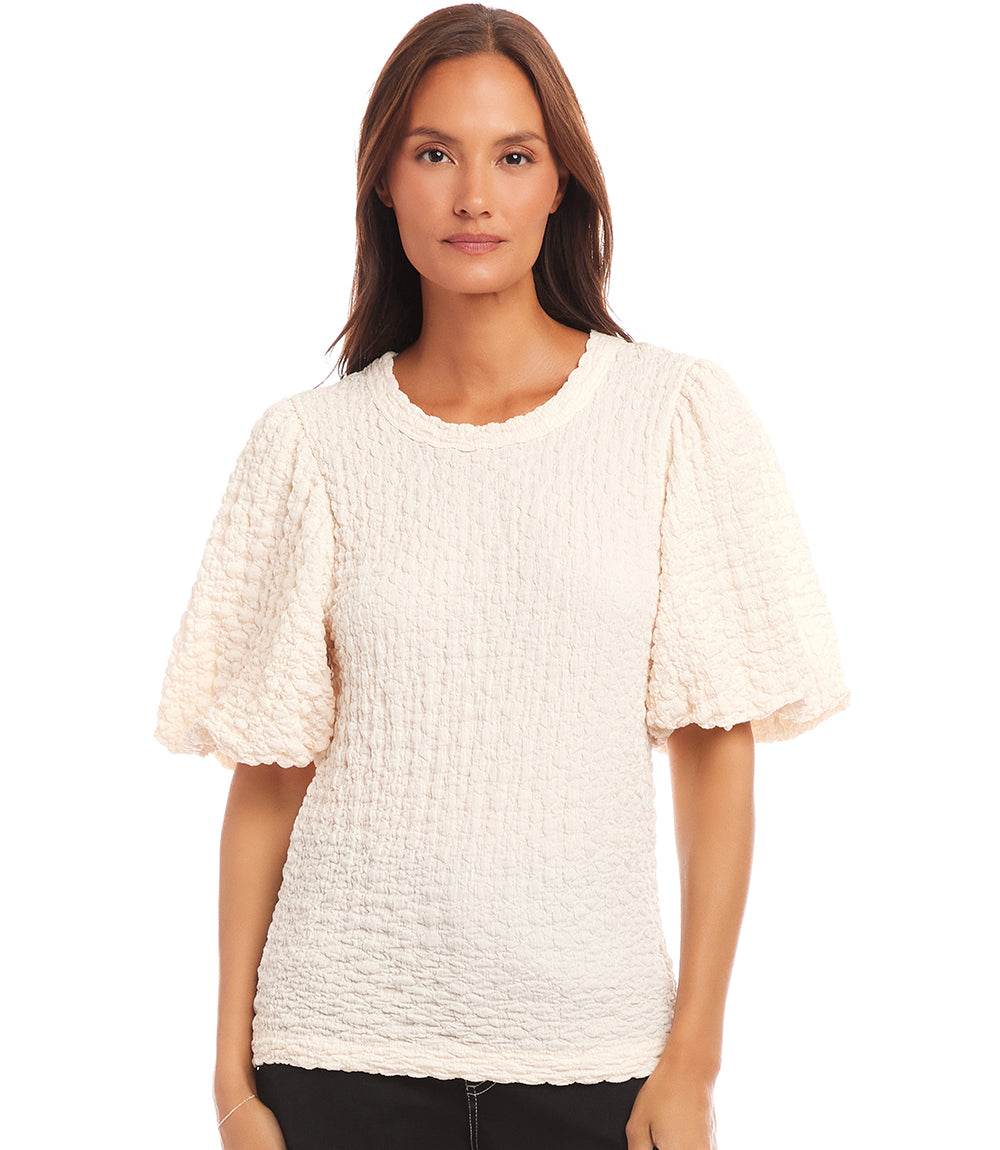 Woman wearing white puff sleeve textured top with bubble knit design and crew neck