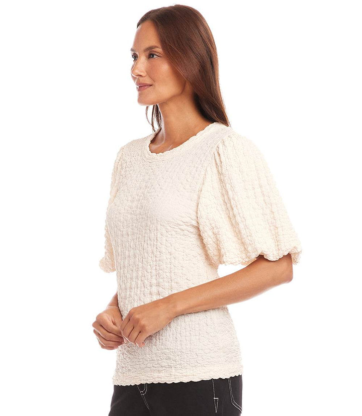 Woman wearing cream puff sleeve textured top with bubble knit detail and crew neck
