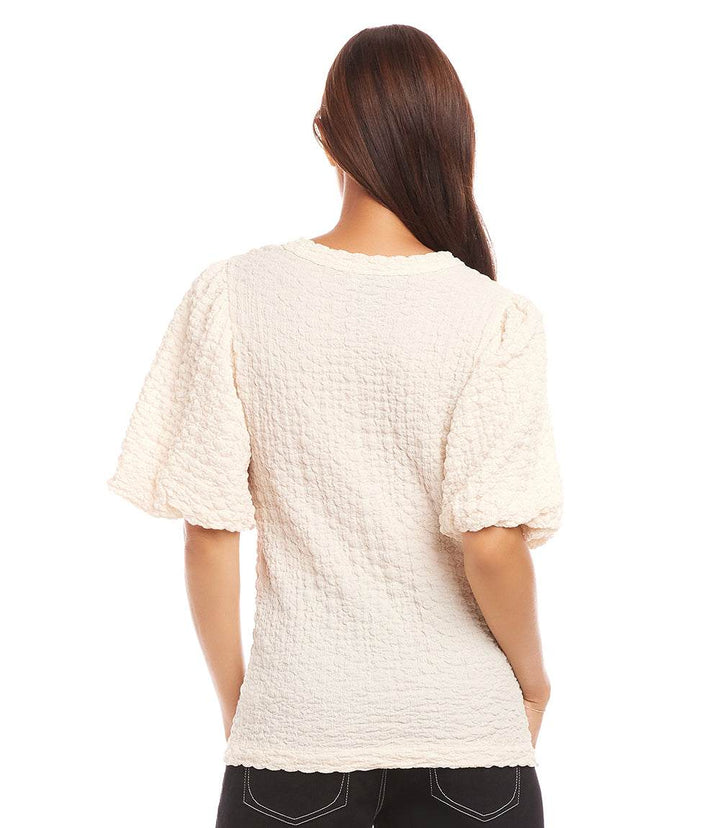 Woman wearing a white puff sleeve textured top with bubble knit detail viewed from the back