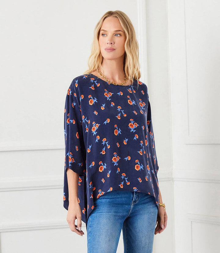 Navy Flare Hem Top with orange carnation print, boat neck, flare sleeves, and double pointed hem, styled with blue jeans.