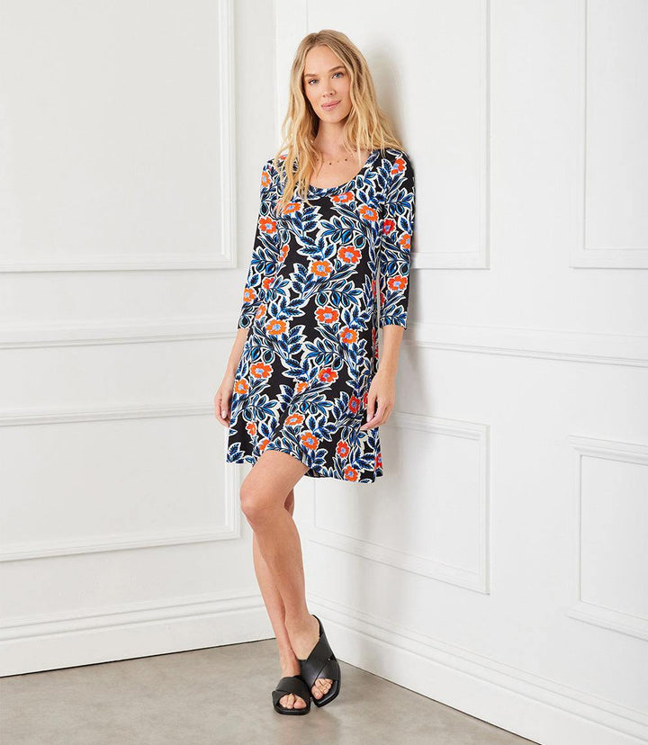 Woman wearing a black 3/4 sleeve A-line dress with vibrant California poppy print and scoop neck.