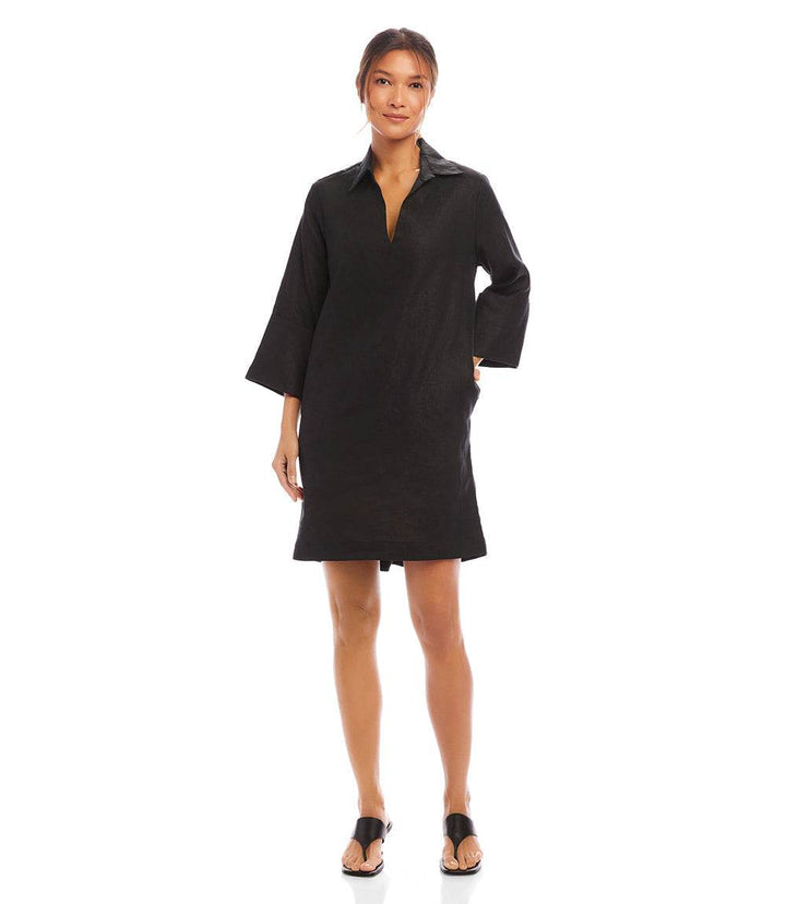 Woman wearing black cuffed sleeve linen dress with collared neckline and side pockets