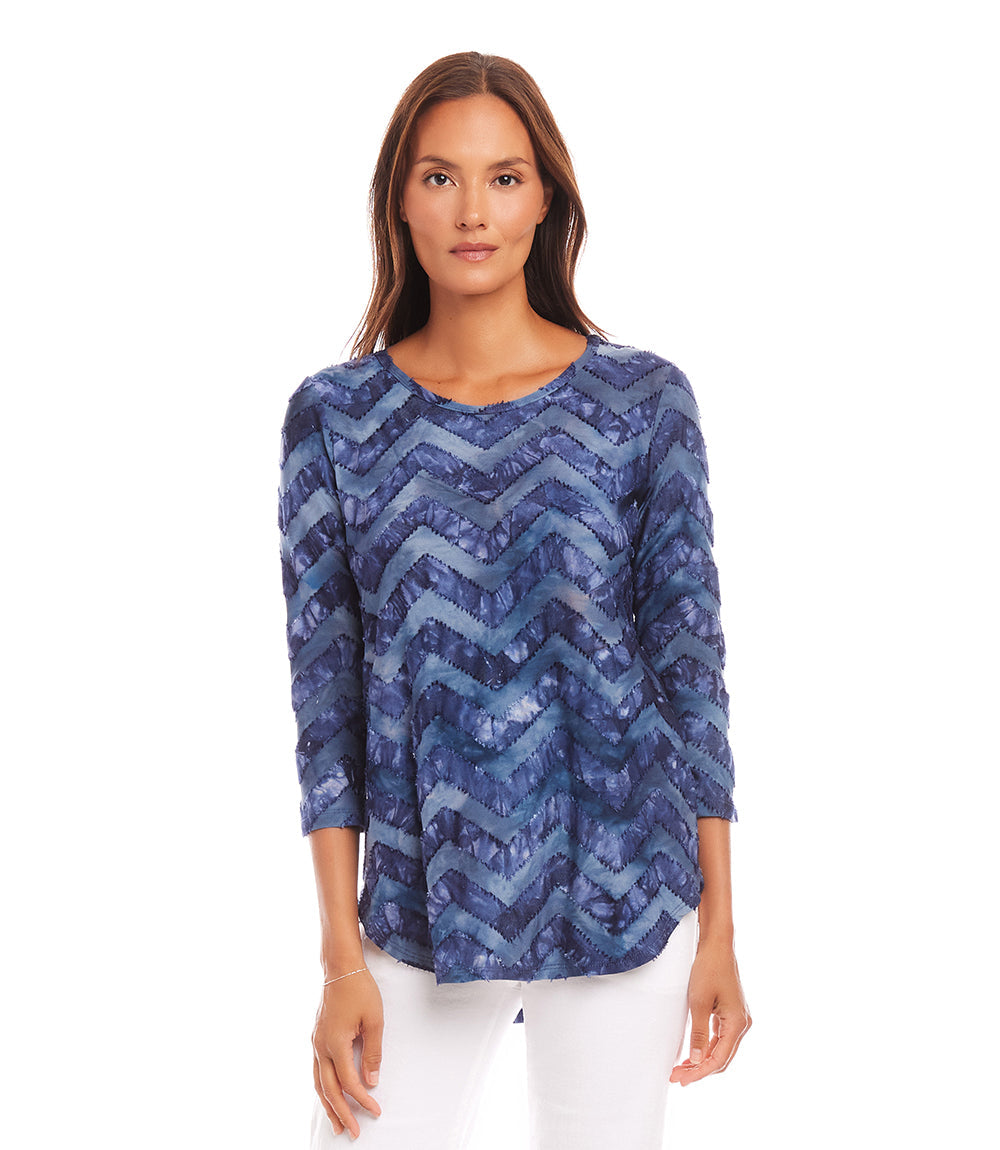 Woman wearing blue zigzag tie-dye 3/4 sleeve burnout shirttail top with scoop neckline and relaxed fit