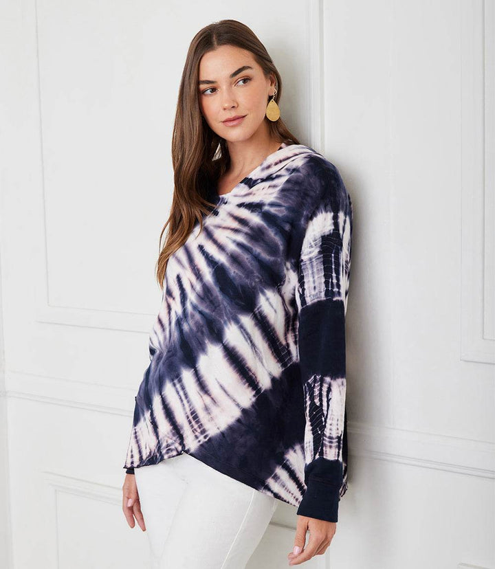 Woman wearing a relaxed fit tie dye asymmetric hem hoodie with drop shoulder sleeves and crew neck.