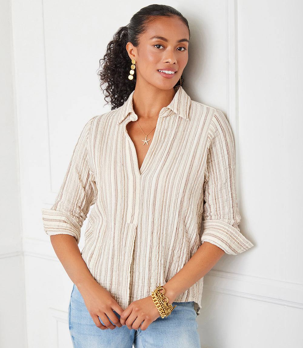 Woman wearing metallic stripe ruched sleeve shirt in textured woven gauze fabric with collared neckline and shirttail hem.