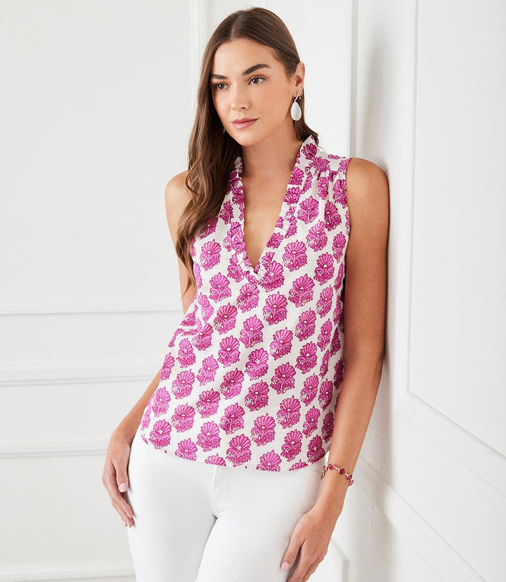 Woman wearing sleeveless ruffle trim top with pink batik flower print and V-neckline.