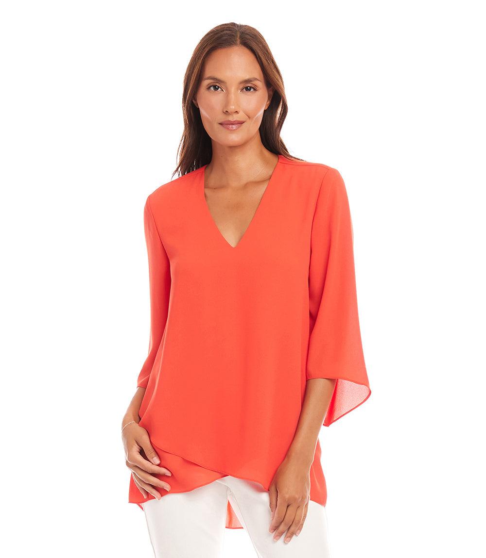 Woman wearing a petite size orange bracelet sleeve asymmetric top with V-neck and layered hem