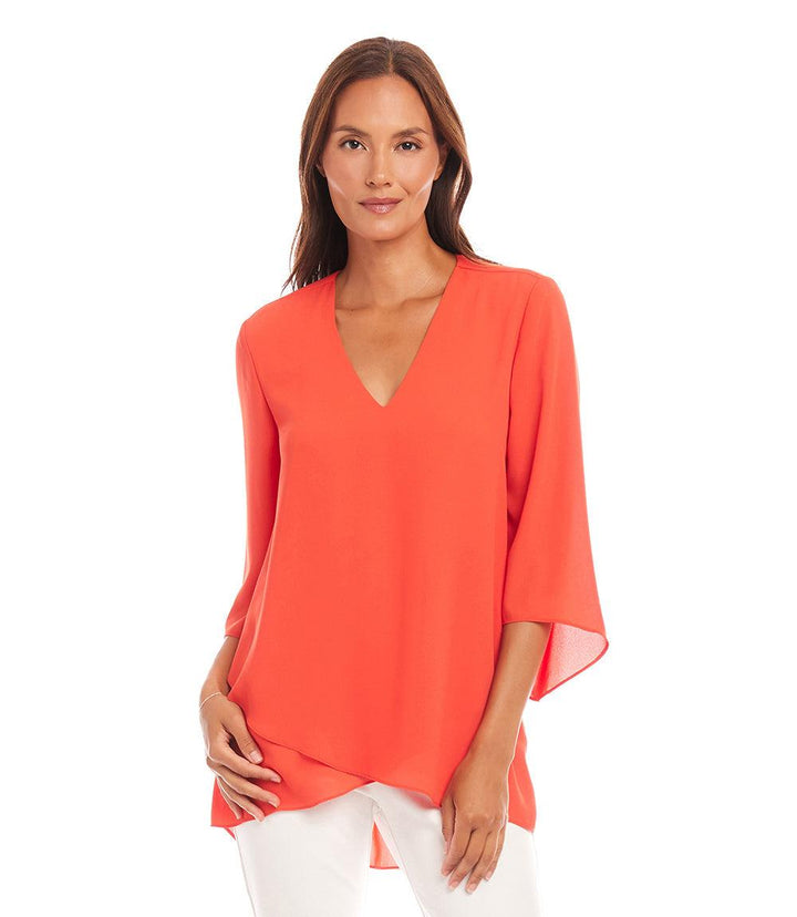 Woman wearing a petite size orange bracelet sleeve asymmetric top with V-neck and layered hem