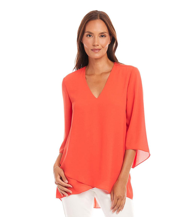 Woman wearing a vibrant orange bracelet sleeve asymmetric top with V-neck and layered hem.