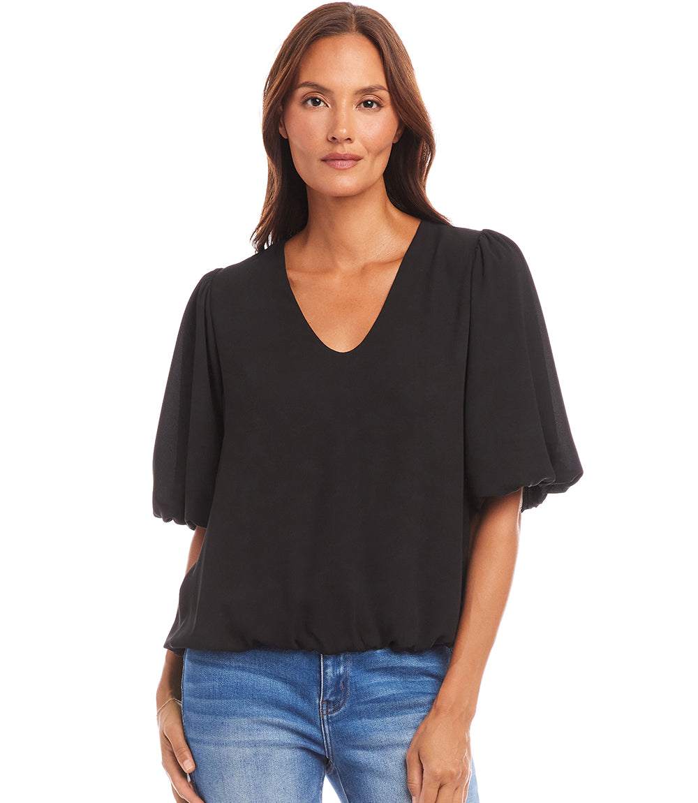 Black puff sleeve top with V-neck and elasticized hem worn by woman