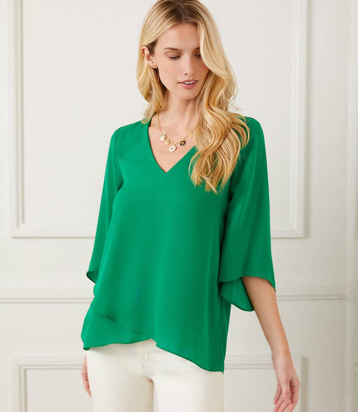 Woman wearing green silky crepe Bracelet Sleeve Asymmetric Top with V-neck and layered asymmetrical hem