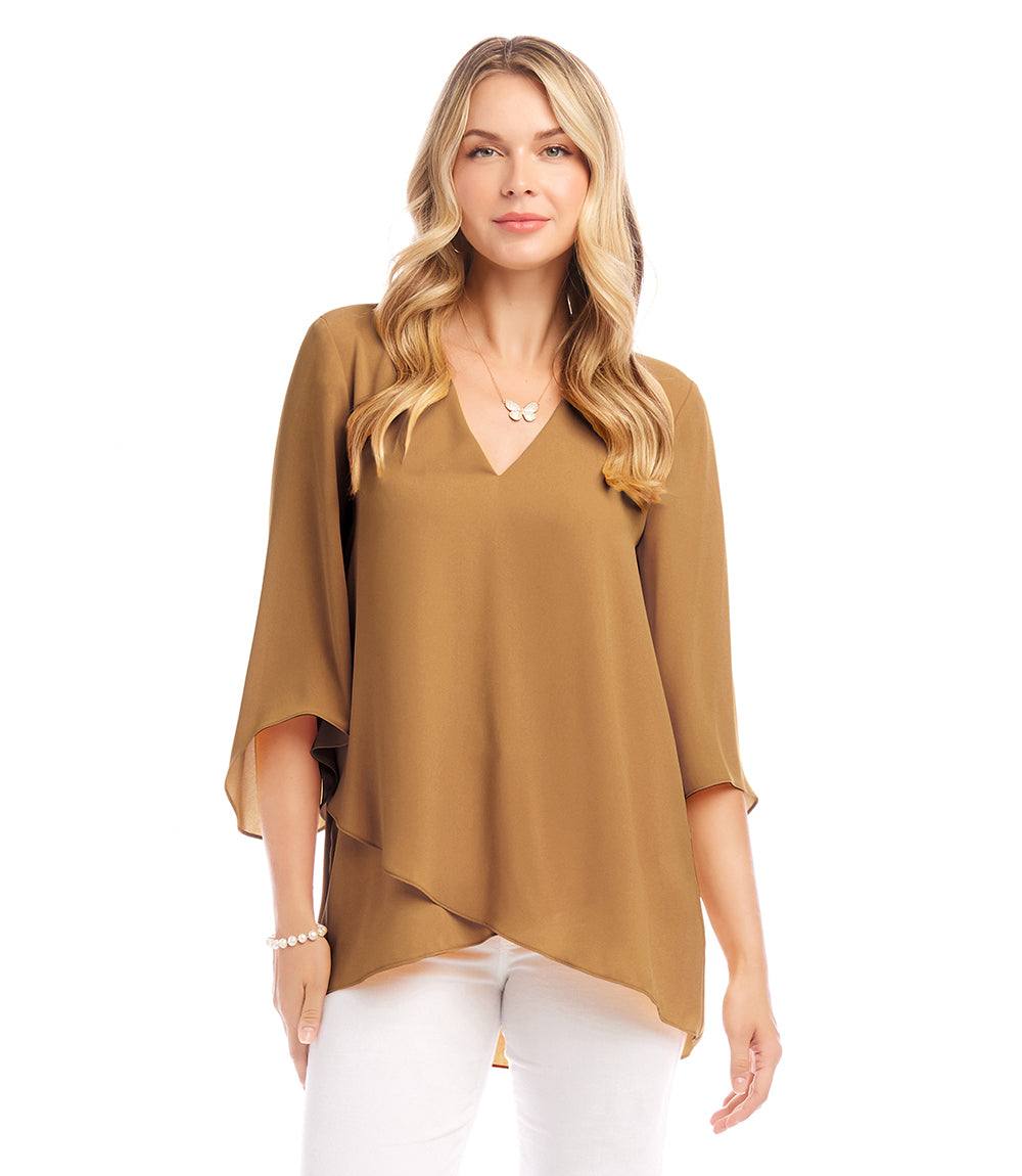 Woman wearing a brown Bracelet Sleeve Asymmetric Top with V-neck, flare sleeves, and layered asymmetrical hem paired with white pants.